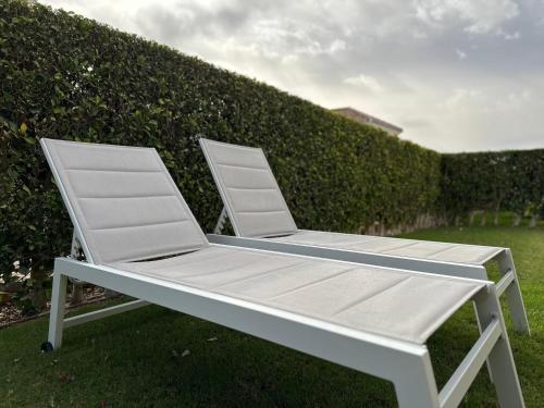 a white chair sitting in the grass next to a hedge at Spacious Villa - DN32LT in Torre-Pacheco