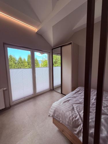 a bedroom with a bed and two large windows at Apartament 59 Bystra Park in Bystra