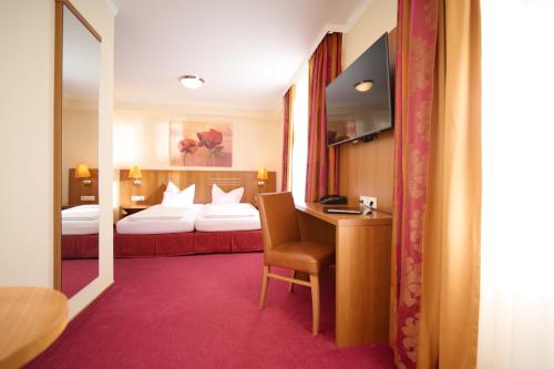 una camera d'albergo con un letto e una scrivania con una sedia di Hotel Vis à vis a Lindau