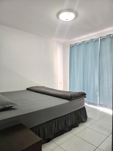 a bedroom with a bed and a blue curtain at Townhome 44 in Ban Nong Pru