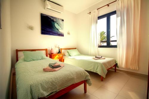 a bedroom with two beds and a window at Niteo House in Costa Teguise