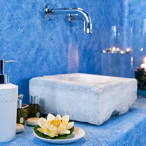 a bathroom with a sink and a flower on a counter at Santorini Roses Suites in Imerovigli