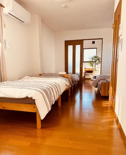 a room with three beds and a wooden floor at 街角TheStreetCorner in Noritake-Shinmachi