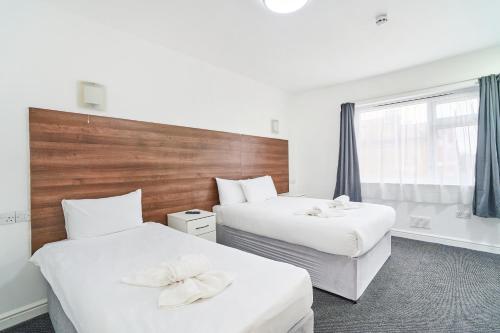 a hotel room with two beds and a window at Park Hotel in Ilford
