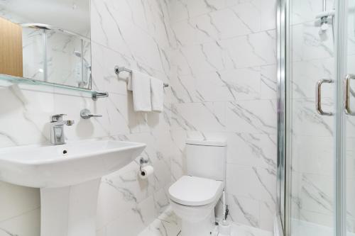 a white bathroom with a toilet and a sink at Park Hotel in Ilford