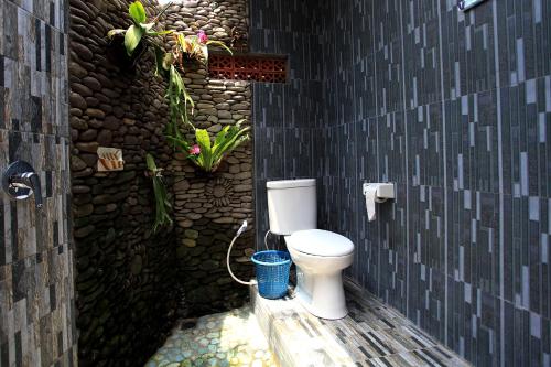 a bathroom with a toilet in a stone wall at Ayu Homestay in Ubud