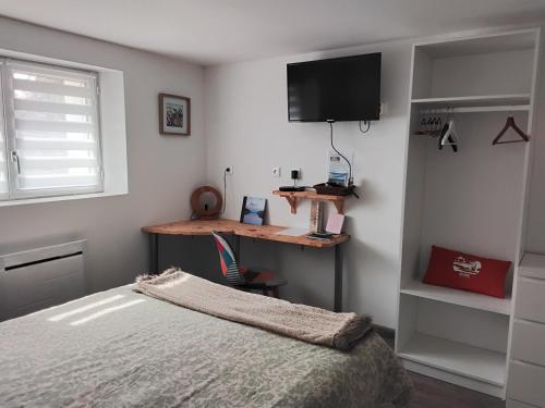 a bedroom with a bed and a desk and a television at Ty Menic in Lesneven