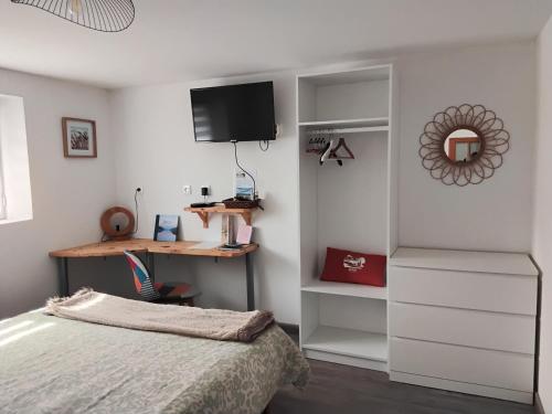 a bedroom with a bed and a desk and a tv at Ty Menic in Lesneven