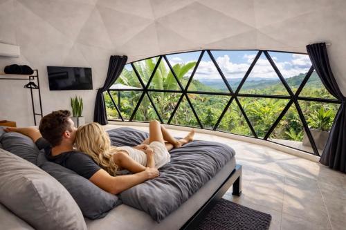 a man and woman laying on a couch in front of a large window at Kayala Domes - Unique Luxury Domes in the Mountains - 4x4 recommended in La Ese