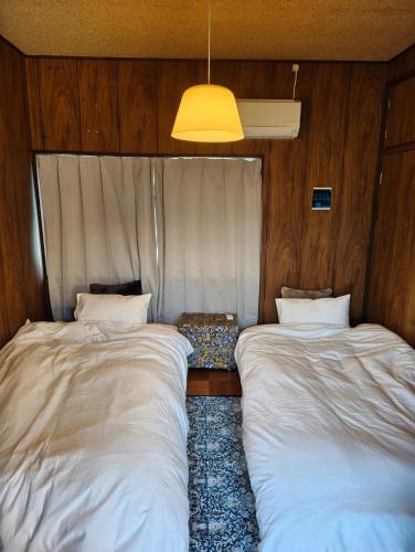 two beds in the corner of a room at Walkable retro town , Supermarkets nearby,高野口ガッコーチカクのゲストハウス in Hashimoto