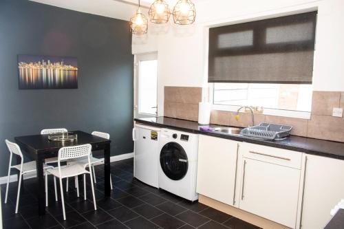a kitchen with a washing machine and a table at 3 Bed - Shefa Homes in Manchester