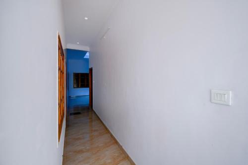 an empty hallway with a white wall and wooden floors at HOTEL O SAV INN in Bhauli