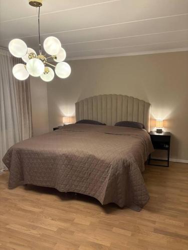 a bedroom with a large bed and a chandelier at Workers Stay - Temporary House Stockholm in Rönninge