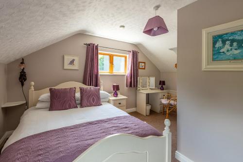 a bedroom with a bed with purple sheets and a window at The Loft in Redcross