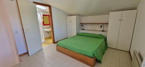 a bedroom with a green bed and a bathroom at Best Holidays Pineta in Marcelli