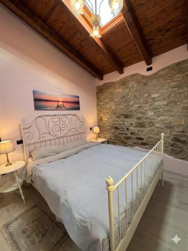 une chambre avec un lit blanc dans un mur de pierre dans l'établissement La Ca' Tòrta - Rustico ristrutturato, à Neviano degli Arduini