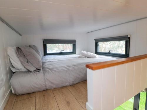 a bed in a small room with two windows at The Tiny Home in Yarm