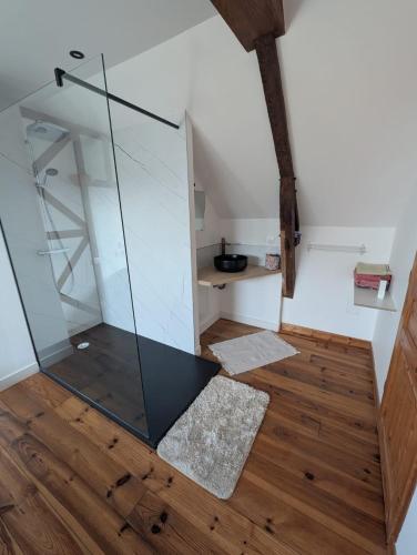 a glass shower in a room with a wooden floor at Gîte des Gatinelles in Erbray