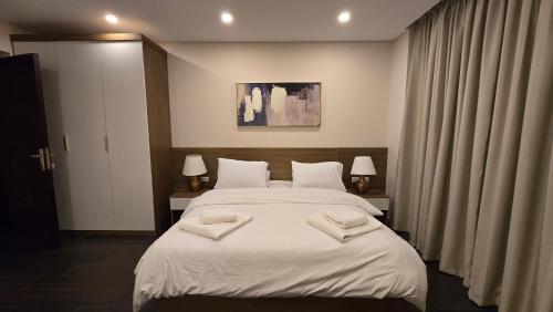 a bedroom with a white bed with two towels on it at Maison 7 Mirage Resort in Cairo