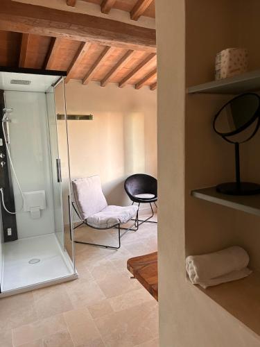 a bathroom with a glass shower and a chair at CasaGozzante in Pienza