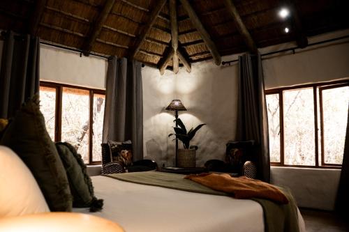 a bedroom with a bed in a room with windows at LittleBush Private Lodge in Hoedspruit