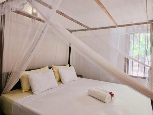 a bedroom with a white bed with a window at The Coast Haven in Tangalle