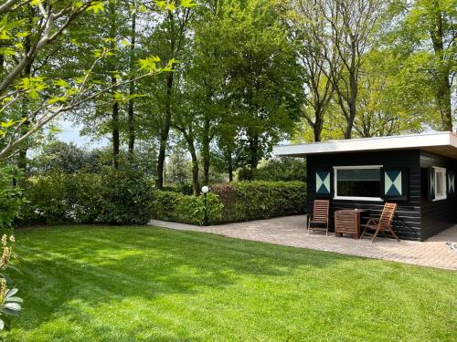 a small black shed with two chairs in a yard at vakantiehuisje Zusje met eigen sauna in Bruchterveld