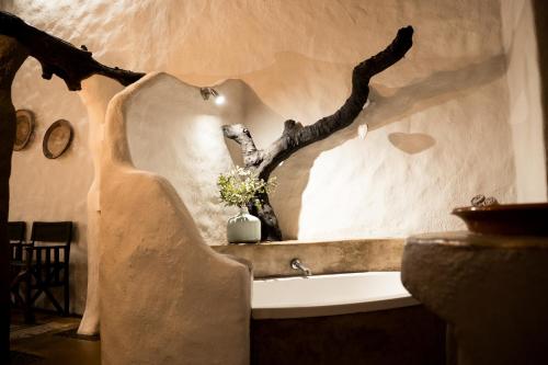 a bathroom with a tree branch on the wall at LittleBush Private Lodge in Hoedspruit