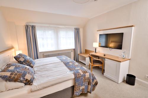 a bedroom with a bed and a desk and a television at Kleinhuis Hotel Mellingburger Schleuse in Hamburg