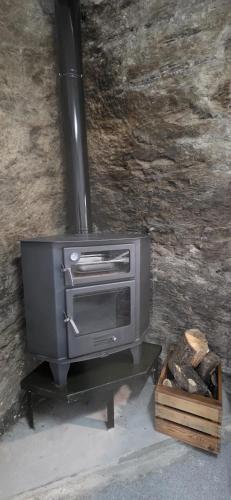 a stove sitting on a stand next to a stone wall at Vivienda Turística de Alojamiento Rural - Labrucena in Abrucena