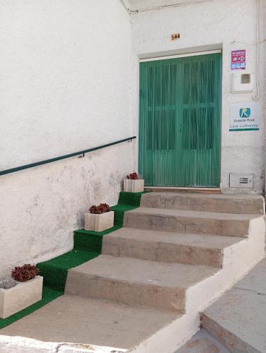 a green door on the side of a building with stairs at Vivienda Turística de Alojamiento Rural - Labrucena in Abrucena