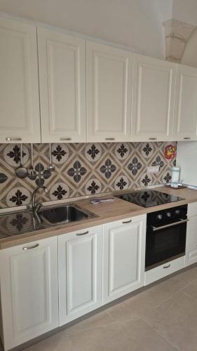 a kitchen with white cabinets and a sink at Casa Coppaiaia - Spaziosa e luminosa nel centro storico in Martina Franca
