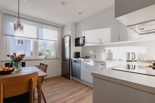 a kitchen with white cabinets and a table with chairs at Huskvarna Apartments in Huskvarna