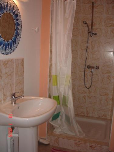 a bathroom with a sink and a shower with a shower curtain at villa les Grenadines in Entre-Deux