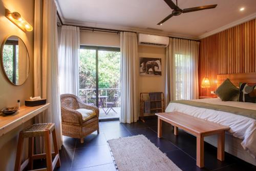a bedroom with a bed and a table and a window at Buffalo Brooke in Hectorspruit