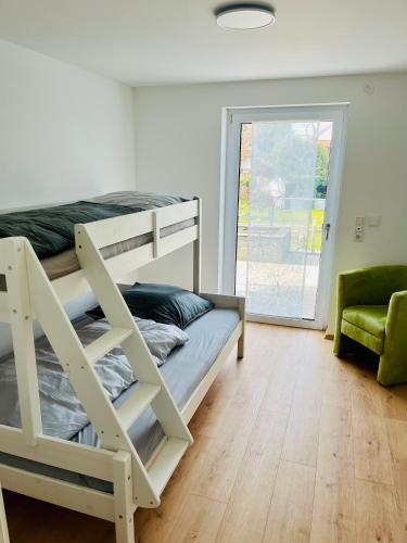 a bedroom with a bunk bed and a green chair at Auszeit im Grünen, ideal für Ausflüge ins Legoland, Allgäu oder Skylinepark in Waltenhausen