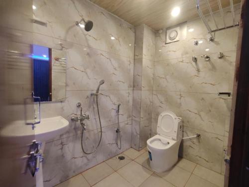 a bathroom with a shower and a toilet and a sink at SB Royal Inn in Mysore