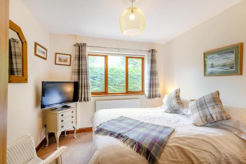 a bedroom with a bed and a tv and a window at 4 Bed in Tywyn oc-23385 in Llanfihangel-y-Pennant