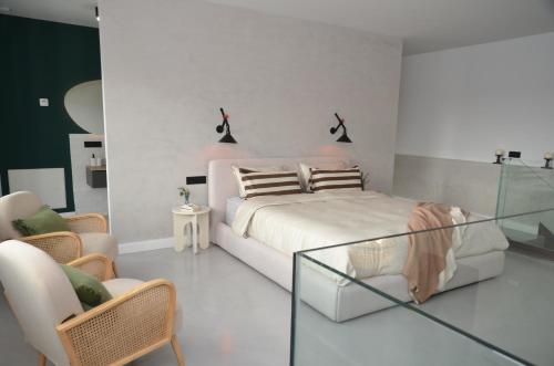a white bedroom with a bed and a chair at Búnker de Pepa in Zamora