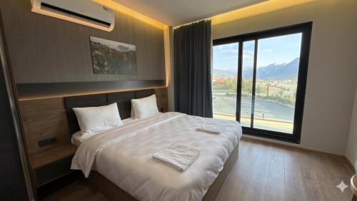 a bedroom with a large bed with a large window at Shingelbana Resort in Rawandoz