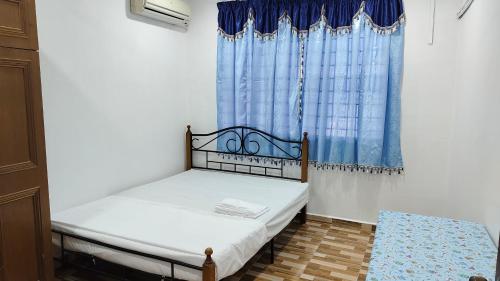 a small bedroom with a bed and a blue curtain at Seetha's Homestay in Lunas
