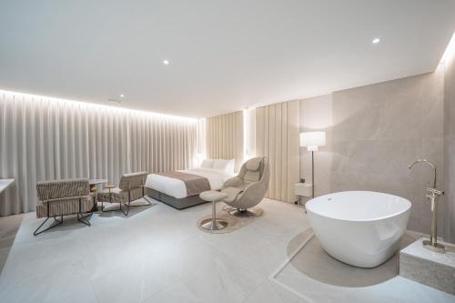 a hotel room with a bed and a bath tub at Daegu Hyeonpung Prana Hotel in Daegu