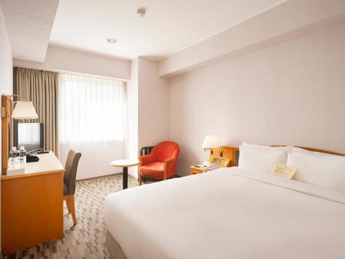 a hotel room with a bed and a desk and chair at Hotel Sunroute Taipei in Taipei