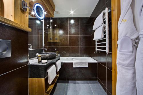 een badkamer met een wastafel en een bad bij Hotel Beauregard in La Clusaz