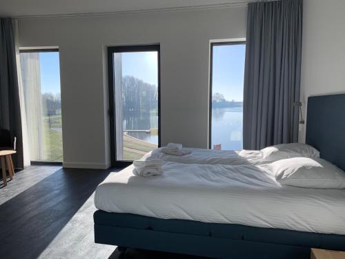 ein Schlafzimmer mit einem großen Bett und großen Fenstern in der Unterkunft Domein Polderwind in Zuienkerke