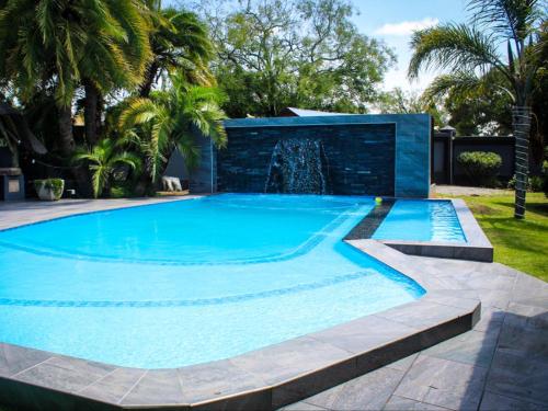 a swimming pool with a fountain in a yard at Haleys Guest House in Benoni