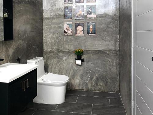 a bathroom with a toilet and some pictures on the wall at The Zain's Pool Villa for 4 pax, Langkawi in Ulu Melaka