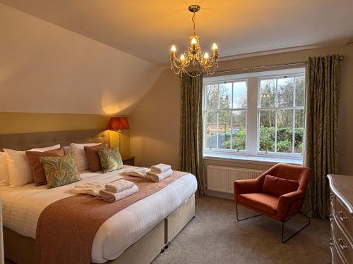 a bedroom with a bed and a chandelier and a chair at Bleaton Hallet House Riverside Escape in Kingseat