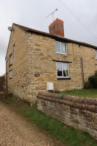 a brick house with two windows and a brick wall at Plum Cottage in Cottesmore