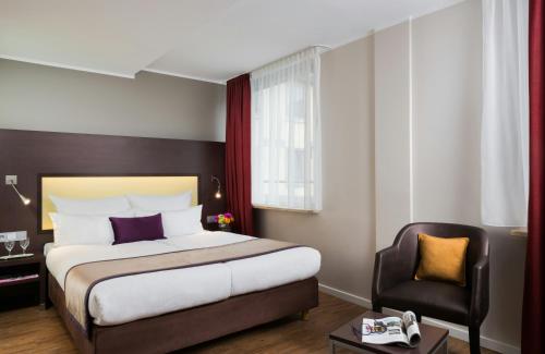 a hotel room with a bed and a chair at Leonardo Hotel München City Center in Munich